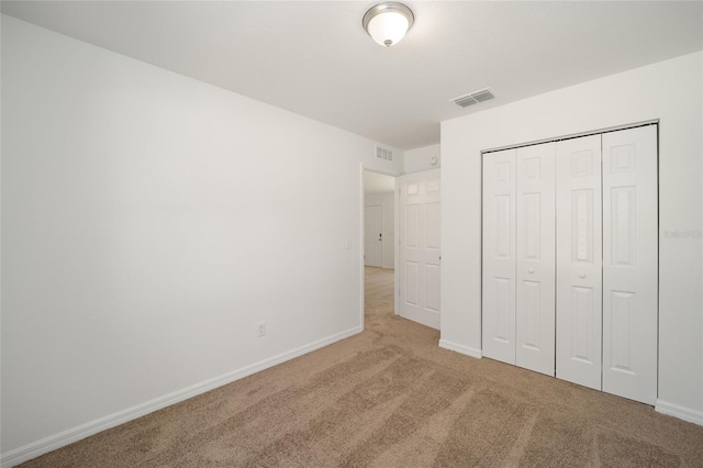 unfurnished bedroom with light colored carpet and a closet