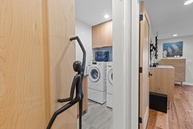 clothes washing area with separate washer and dryer and light hardwood / wood-style flooring