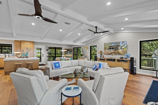 living room featuring vaulted ceiling with beams, light hardwood / wood-style flooring, and a healthy amount of sunlight