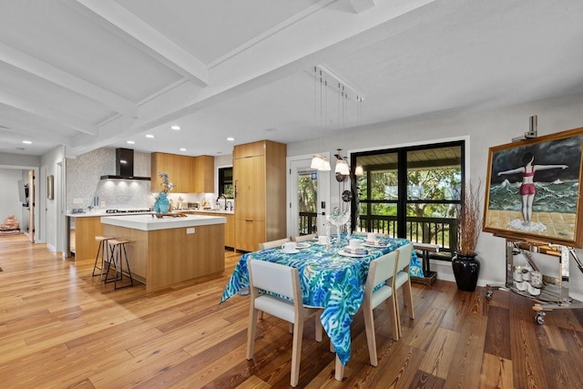 dining area with beam ceiling, french doors, light hardwood / wood-style floors, and sink