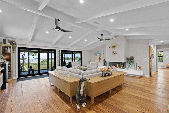 living room featuring lofted ceiling with beams, light hardwood / wood-style floors, and ceiling fan