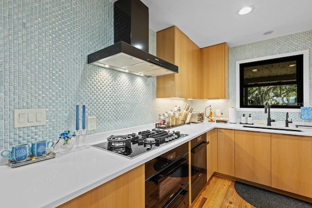 kitchen with gas cooktop, backsplash, wall chimney exhaust hood, sink, and oven