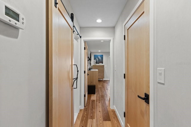 corridor featuring a barn door and light hardwood / wood-style floors