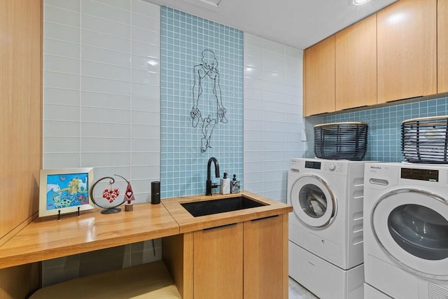 washroom with cabinets, separate washer and dryer, and sink