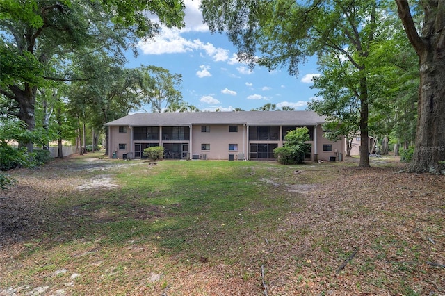 back of property featuring a sunroom and a lawn