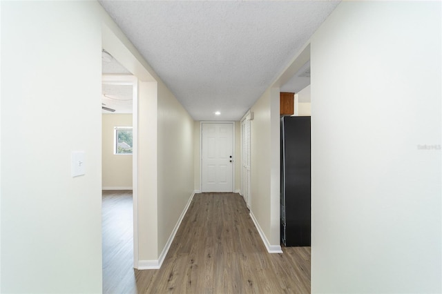 corridor featuring a textured ceiling and light wood-type flooring