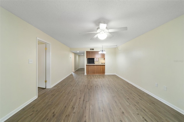 unfurnished living room featuring ceiling fan, dark hardwood / wood-style flooring, and a textured ceiling