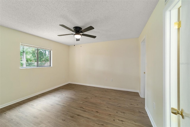 empty room with ceiling fan, dark wood-type flooring, and a textured ceiling