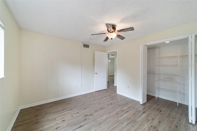 unfurnished bedroom with ceiling fan, light wood-type flooring, a textured ceiling, and a closet