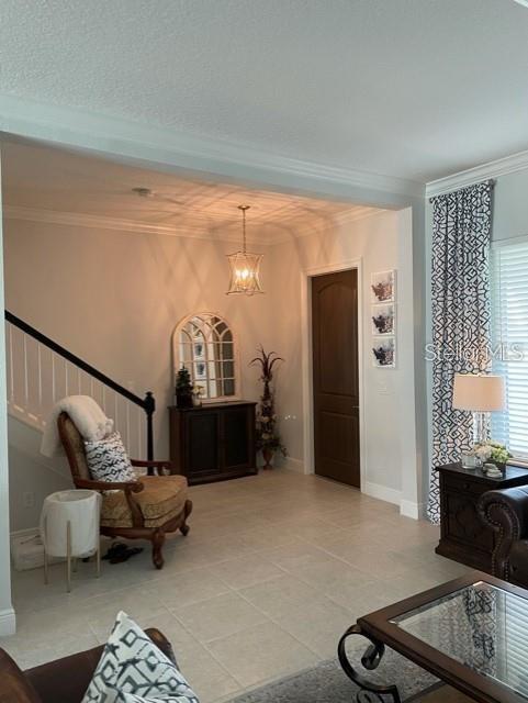 living area featuring a notable chandelier, ornamental molding, and tile floors