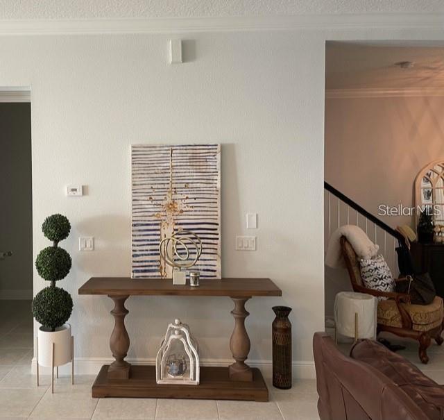 interior details featuring tile flooring, ornamental molding, and a textured ceiling