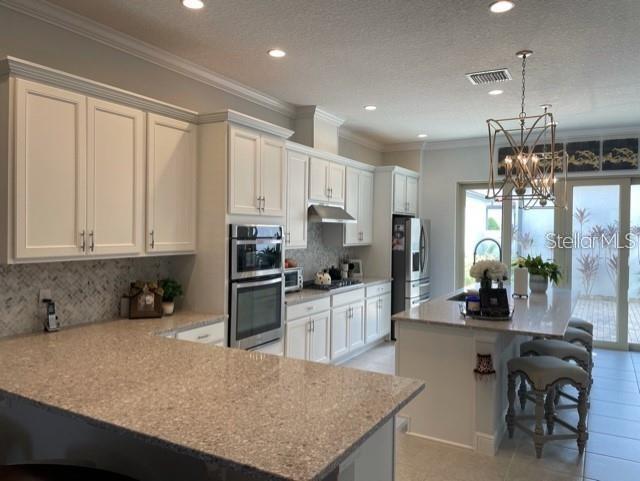 kitchen with a notable chandelier, tasteful backsplash, appliances with stainless steel finishes, sink, and a textured ceiling