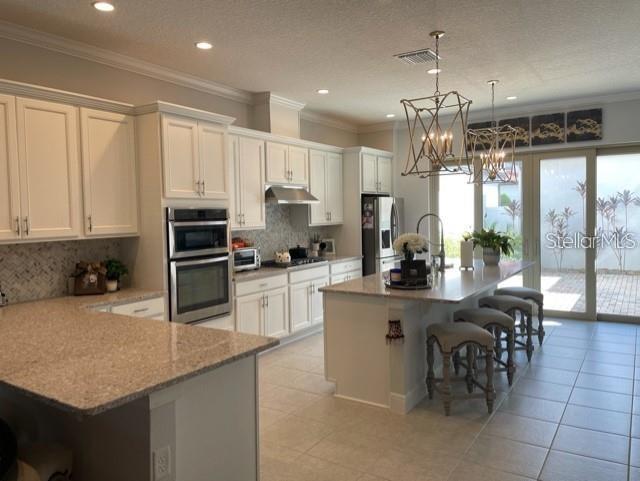 kitchen with hanging light fixtures, crown molding, tasteful backsplash, and appliances with stainless steel finishes