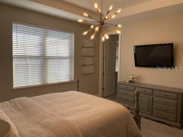 carpeted bedroom featuring a notable chandelier