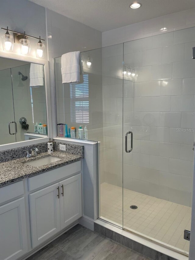 bathroom with walk in shower, hardwood / wood-style flooring, and vanity