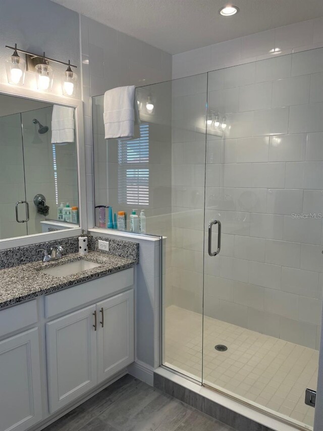 bathroom featuring wood-type flooring, walk in shower, and large vanity