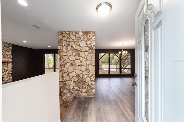 hall with wood-type flooring and a chandelier