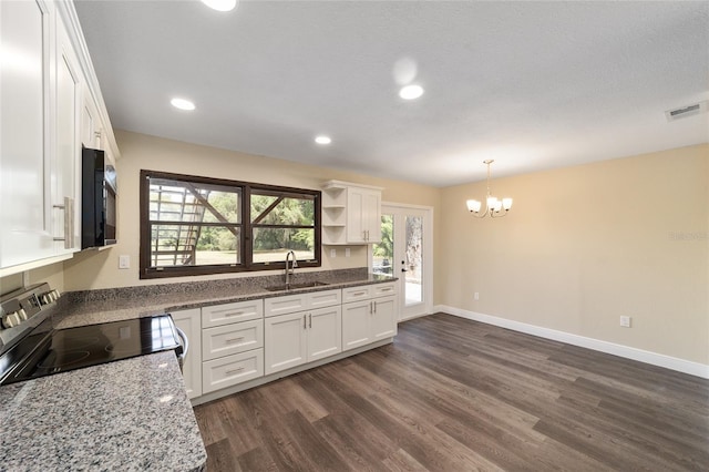 kitchen with white cabinets, sink, hanging light fixtures, stone countertops, and range