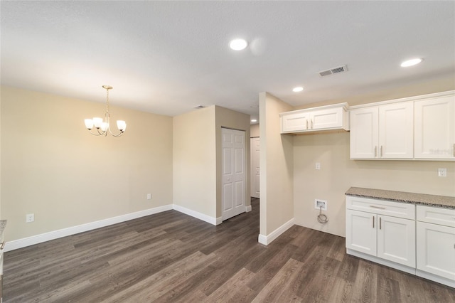 kitchen featuring dark stone countertops, dark wood-type flooring, white cabinets, and hanging light fixtures