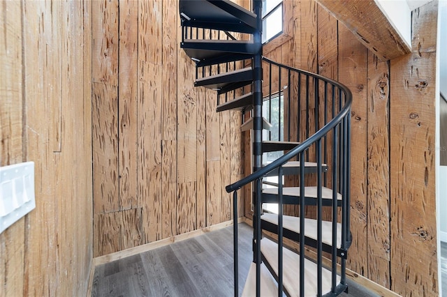 stairway featuring wood-type flooring and wooden walls