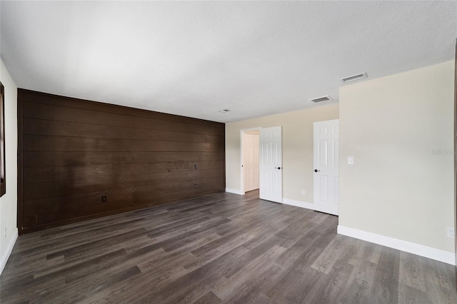 spare room featuring dark hardwood / wood-style floors and wood walls