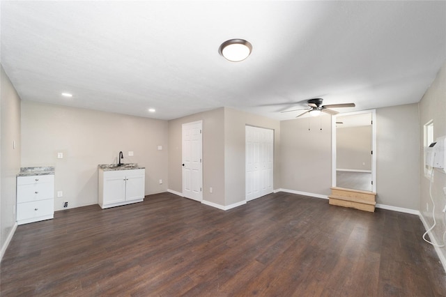 unfurnished living room featuring ceiling fan, dark hardwood / wood-style flooring, and sink