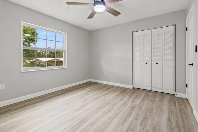 unfurnished bedroom featuring ceiling fan, light hardwood / wood-style flooring, a closet, and a textured ceiling