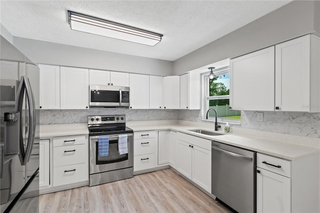 kitchen with appliances with stainless steel finishes, white cabinets, and sink