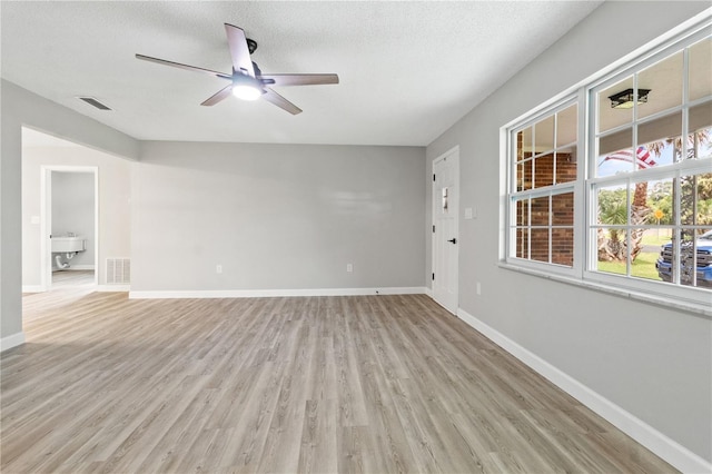 spare room with sink, a textured ceiling, ceiling fan, and light hardwood / wood-style floors