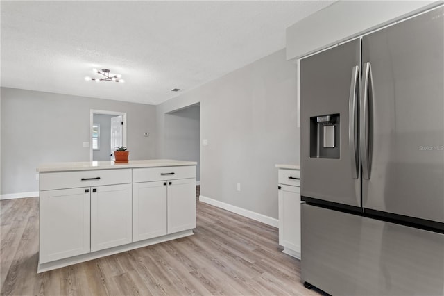 kitchen with white cabinets, stainless steel fridge with ice dispenser, light hardwood / wood-style flooring, and a textured ceiling