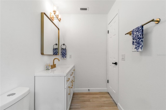 bathroom with toilet, vanity, and hardwood / wood-style flooring