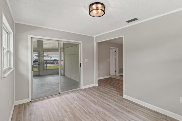 unfurnished room with a textured ceiling, plenty of natural light, and light hardwood / wood-style flooring