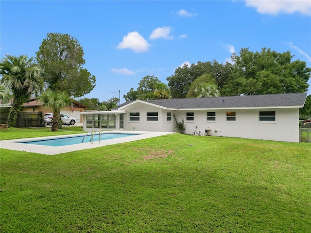 back of property with a sunroom, a yard, and a fenced in pool