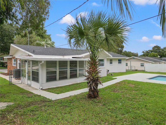 back of property featuring cooling unit, a yard, and a sunroom