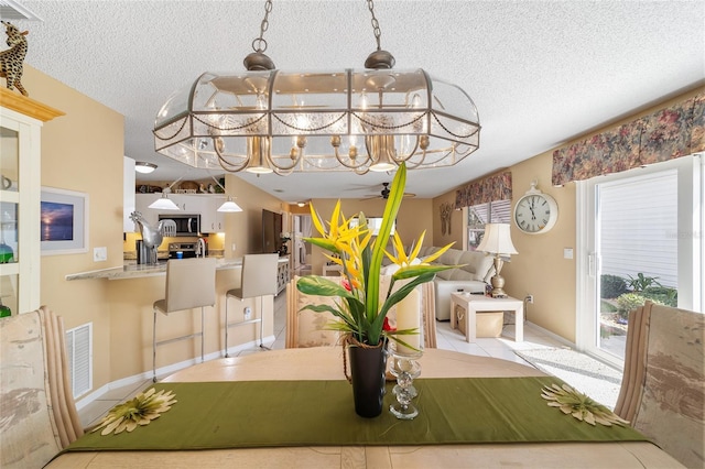 tiled dining space with ceiling fan and a textured ceiling