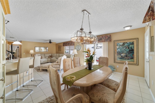 tiled dining area with a textured ceiling and ceiling fan with notable chandelier