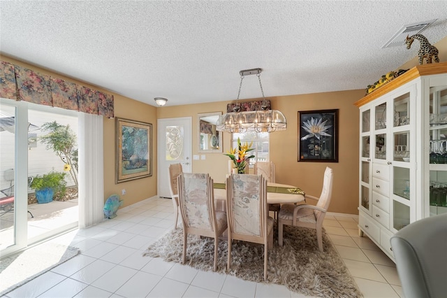 dining space with light tile patterned flooring, a chandelier, and a textured ceiling