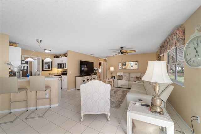 tiled living room with ceiling fan and a textured ceiling