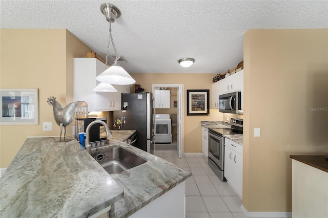 kitchen featuring stainless steel appliances, sink, washer / clothes dryer, white cabinetry, and hanging light fixtures