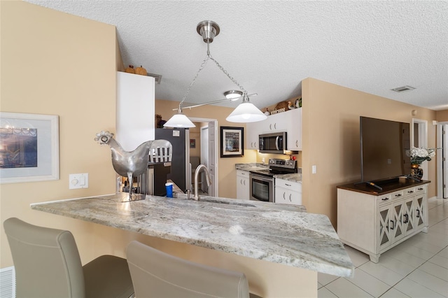 kitchen with a breakfast bar area, white cabinets, stainless steel appliances, and decorative light fixtures