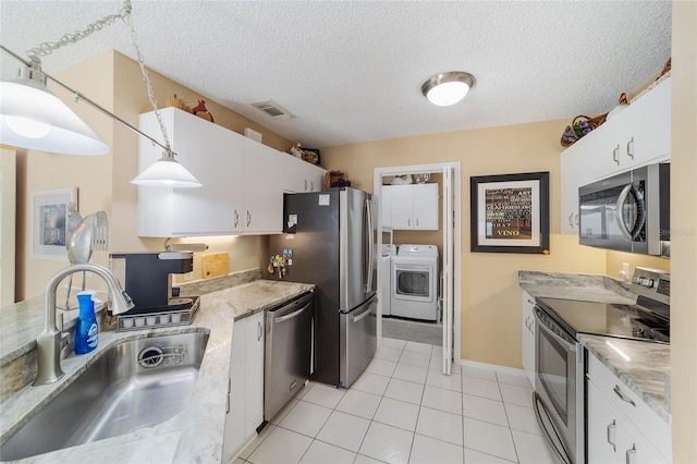 kitchen with pendant lighting, white cabinets, sink, light tile patterned floors, and appliances with stainless steel finishes