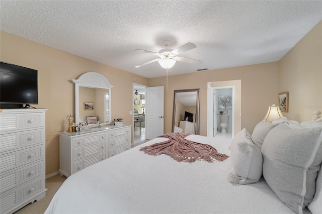 bedroom with ensuite bath, ceiling fan, and a textured ceiling