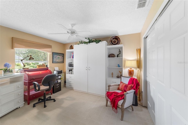 home office featuring ceiling fan, light colored carpet, and a textured ceiling