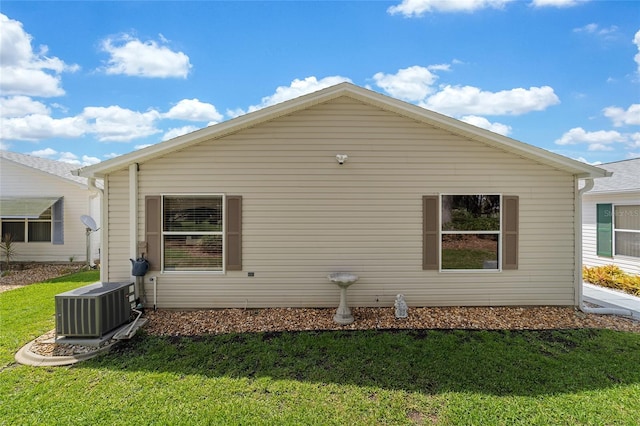 view of side of property featuring a lawn and central AC