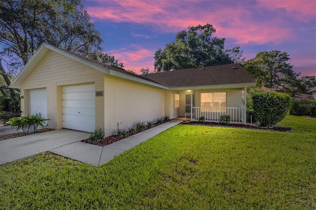 ranch-style home with covered porch, a garage, and a yard