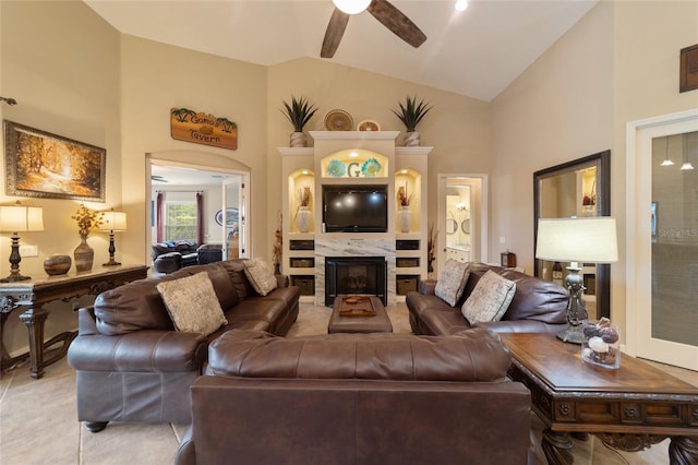 tiled living room with ceiling fan, high vaulted ceiling, and a high end fireplace