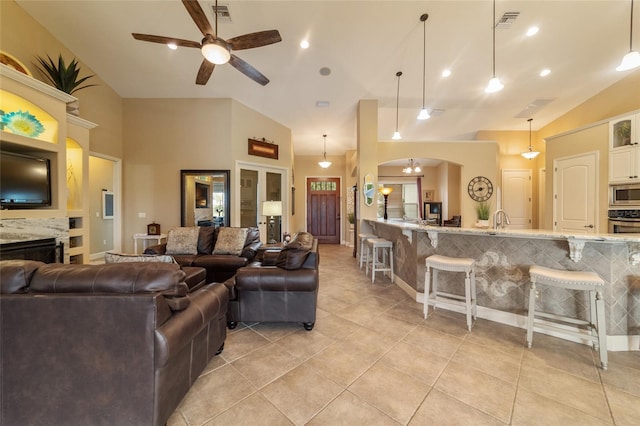 living room featuring ceiling fan, a fireplace, lofted ceiling, and light tile patterned flooring