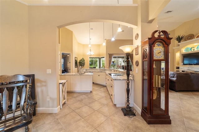 kitchen with black electric cooktop, white cabinets, decorative light fixtures, kitchen peninsula, and light stone counters