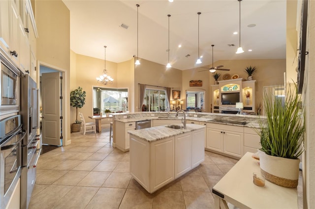 kitchen featuring an island with sink, high vaulted ceiling, pendant lighting, and appliances with stainless steel finishes