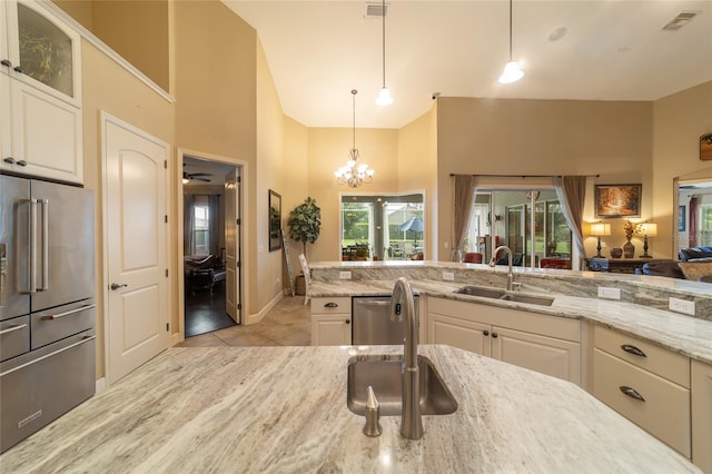 kitchen with appliances with stainless steel finishes, decorative light fixtures, sink, light stone counters, and light tile patterned floors